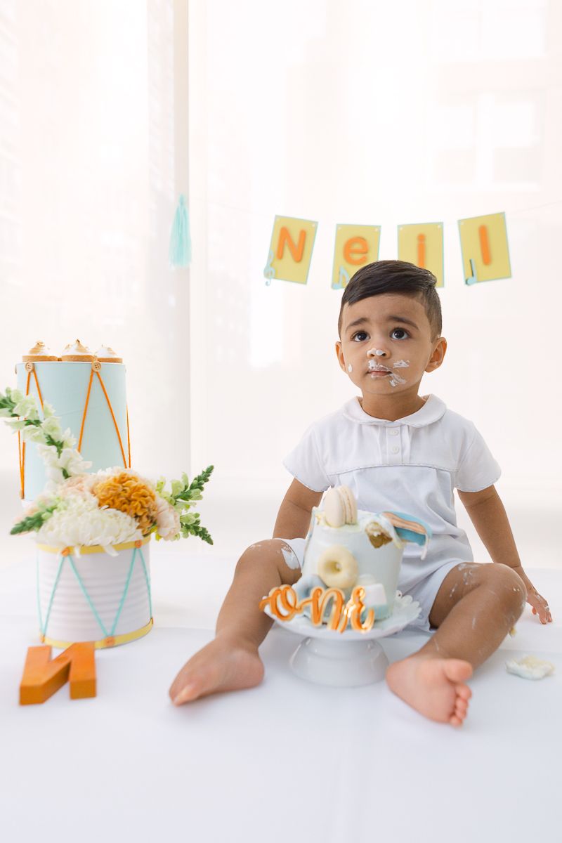 an Indian boy sits next to his birthday cake during a cake smash photo by Paula Ortiz NY Family Photographer
