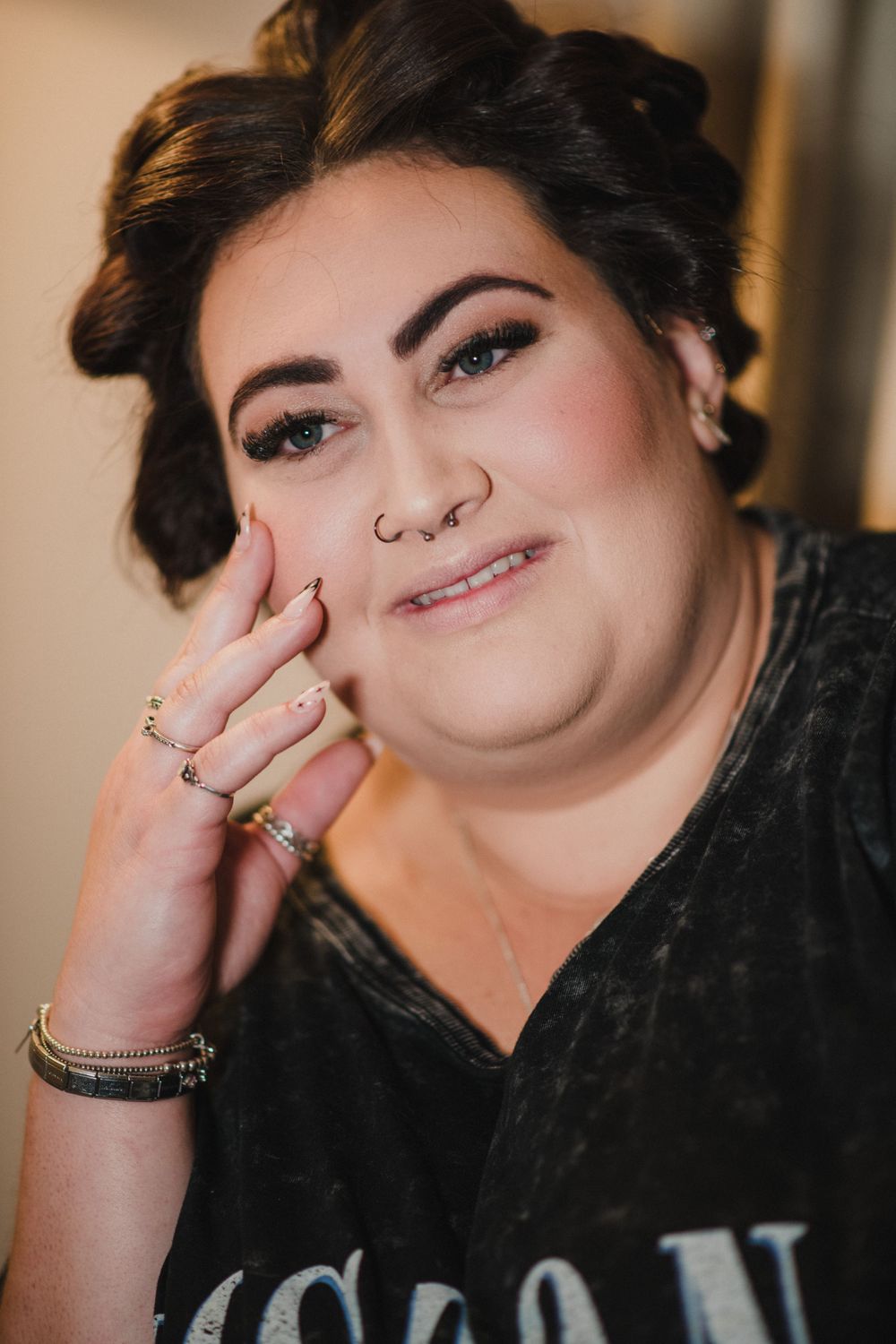 Close up portrait of someone with styled hair wearing black and jewelry.