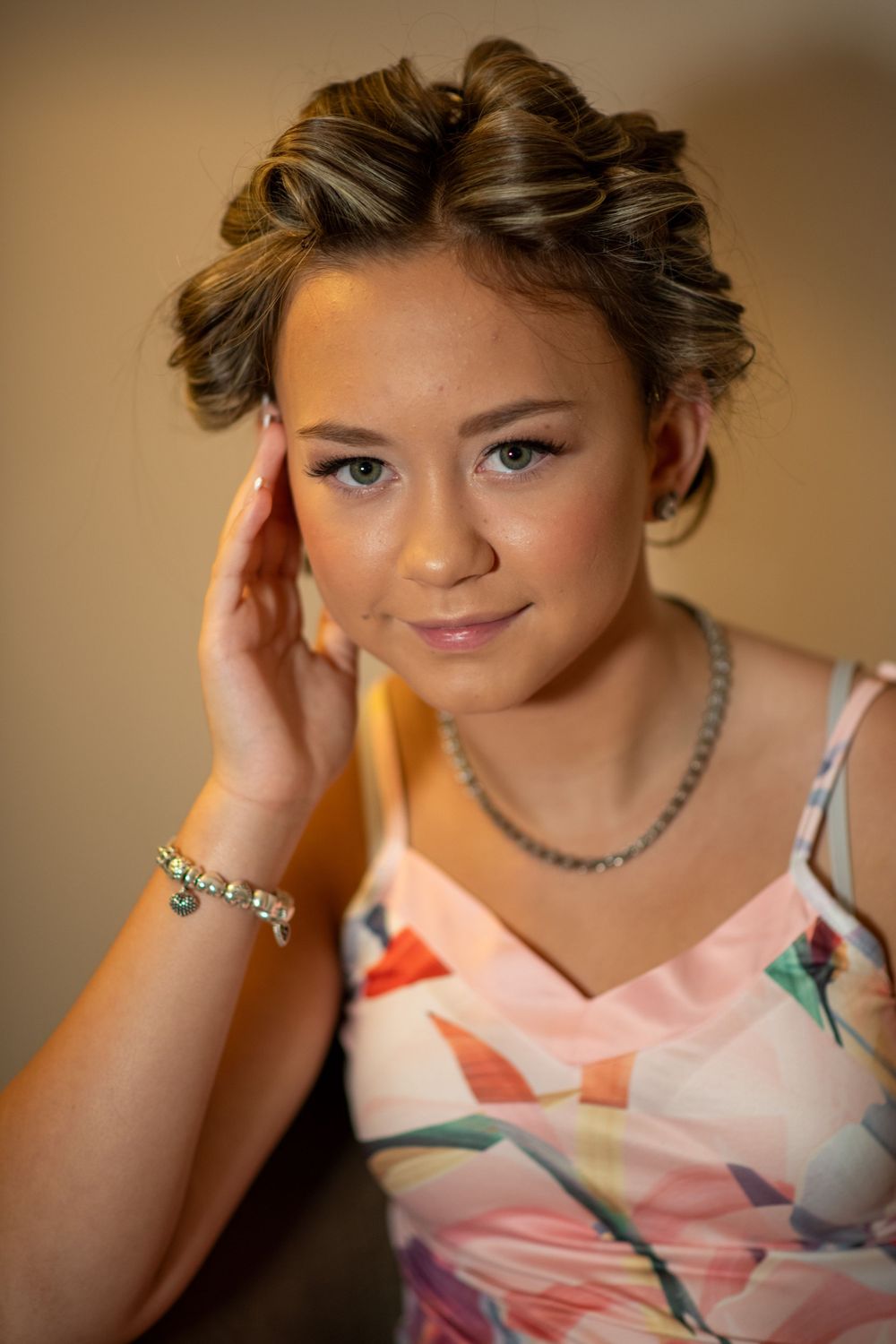 Portrait of someone in a floral dress with styled hair and jewelry.