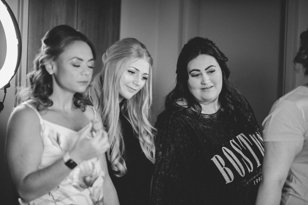 Three women look down at something together in a black and white candid moment.