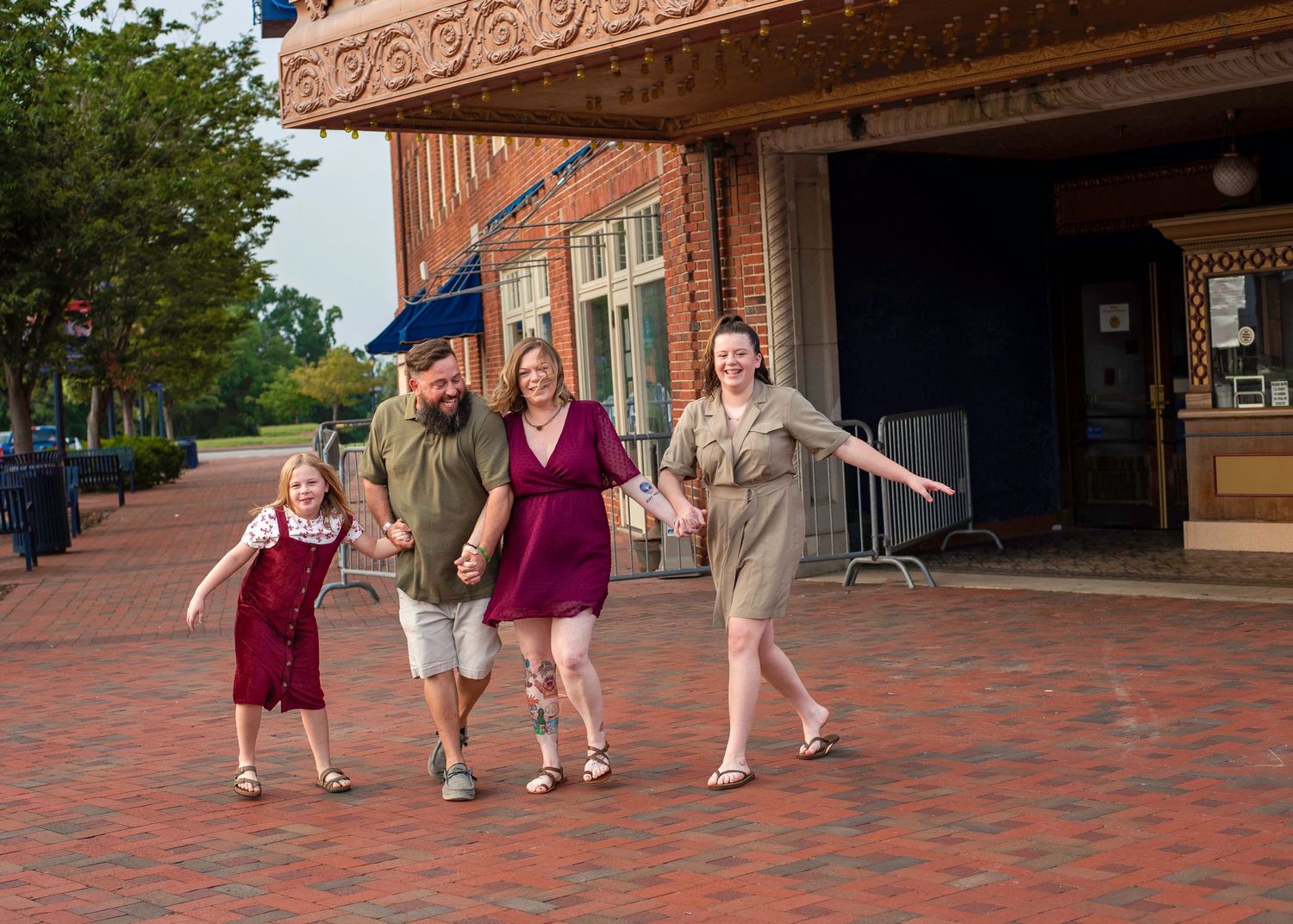 Group walking and laughing together on brick sidewalk outside storefront.