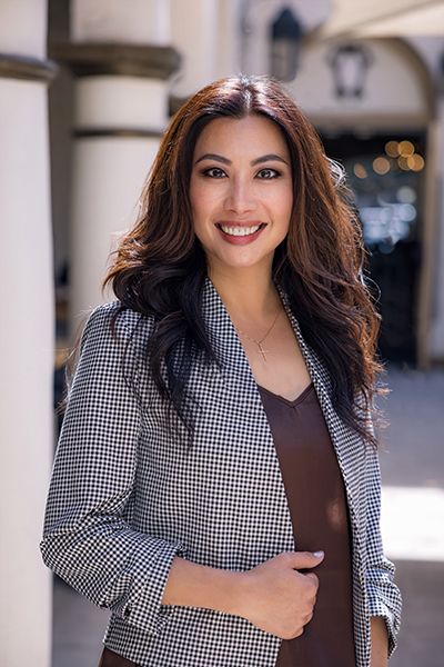 Brunette asian woman wearing black and white jacket smiling