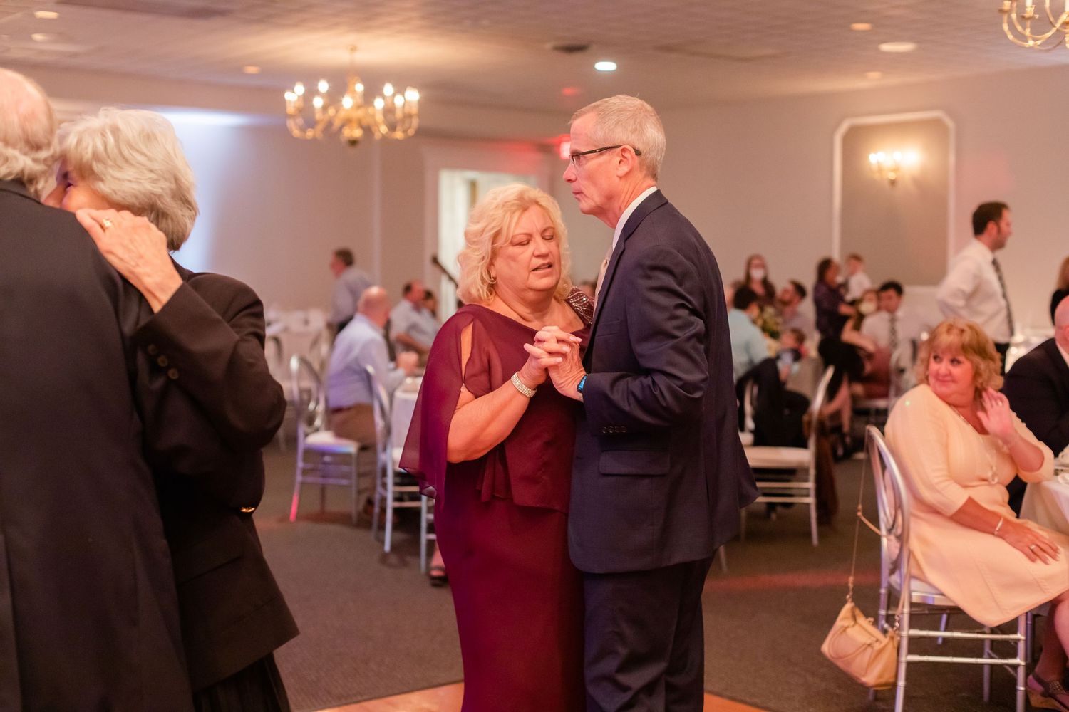 Wedding reception dance floor with elegant lighting and couples dancing in formal attire.