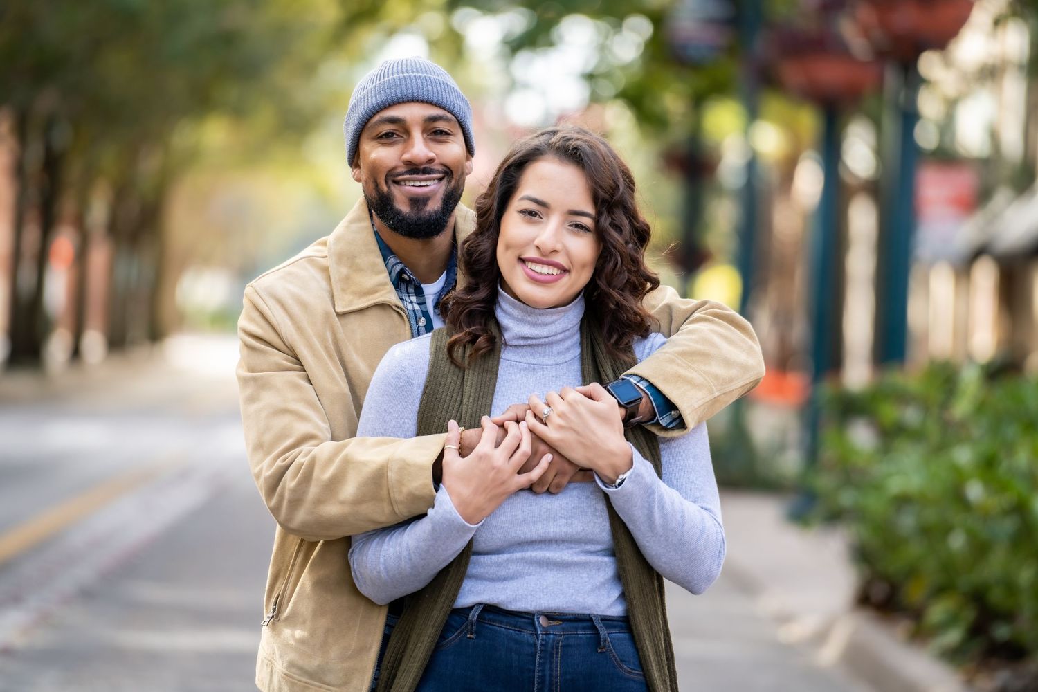 Couple sharing joyful embrace on autumn street with seasonal decorations.
