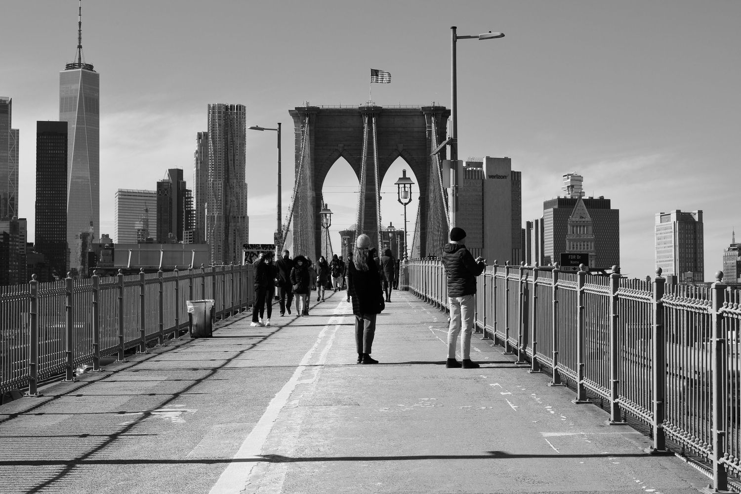 People walking across the Brooklyn Bridge with Manhattan skyline in the background.