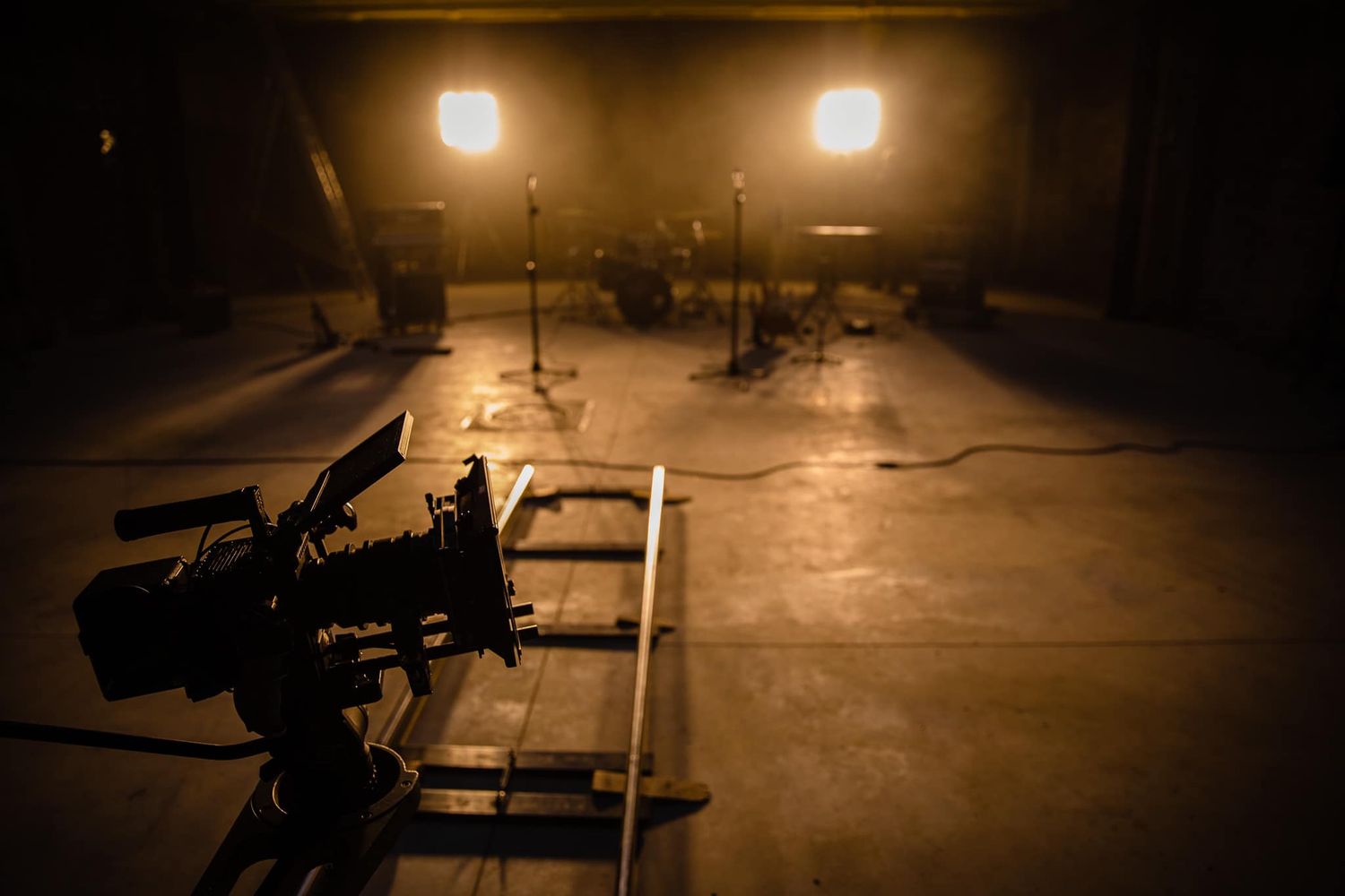 Empty studio space with dramatic spotlights creating pools of light on dark floor.