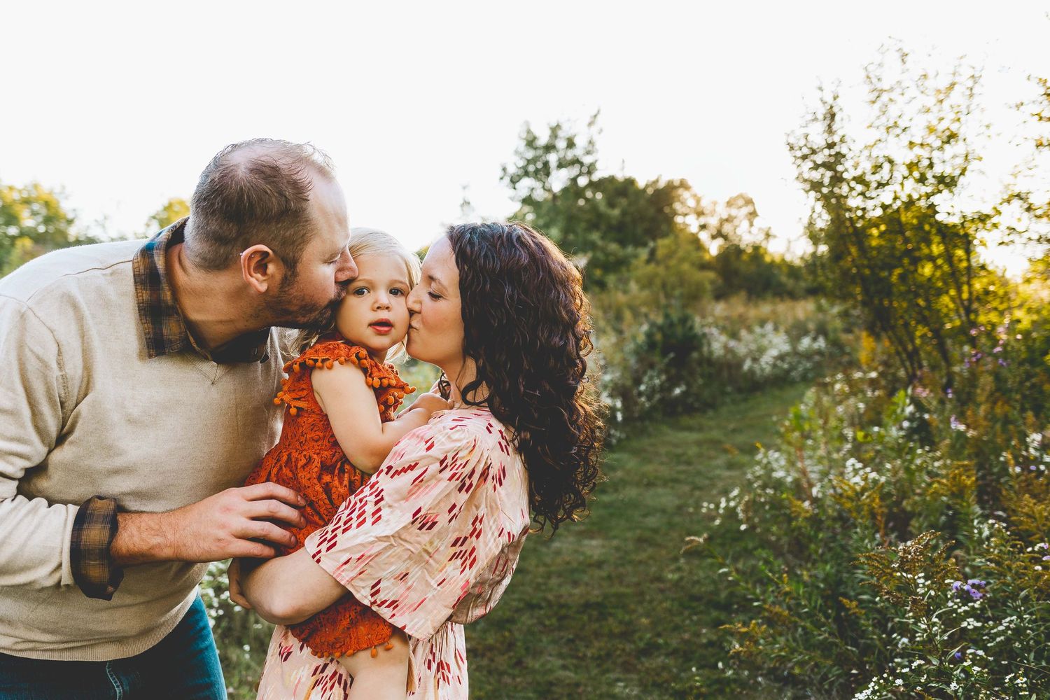 Adorable family giving kisses to their little girl during a family photoshoot at nashotah park wisconsin
