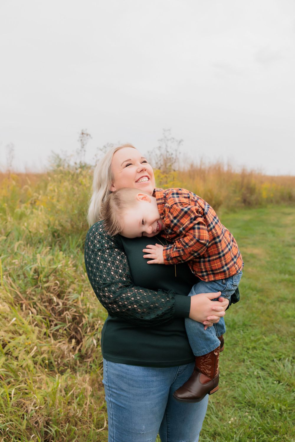 An affectionate embrace captured outdoors with tall autumn grasses in the background.