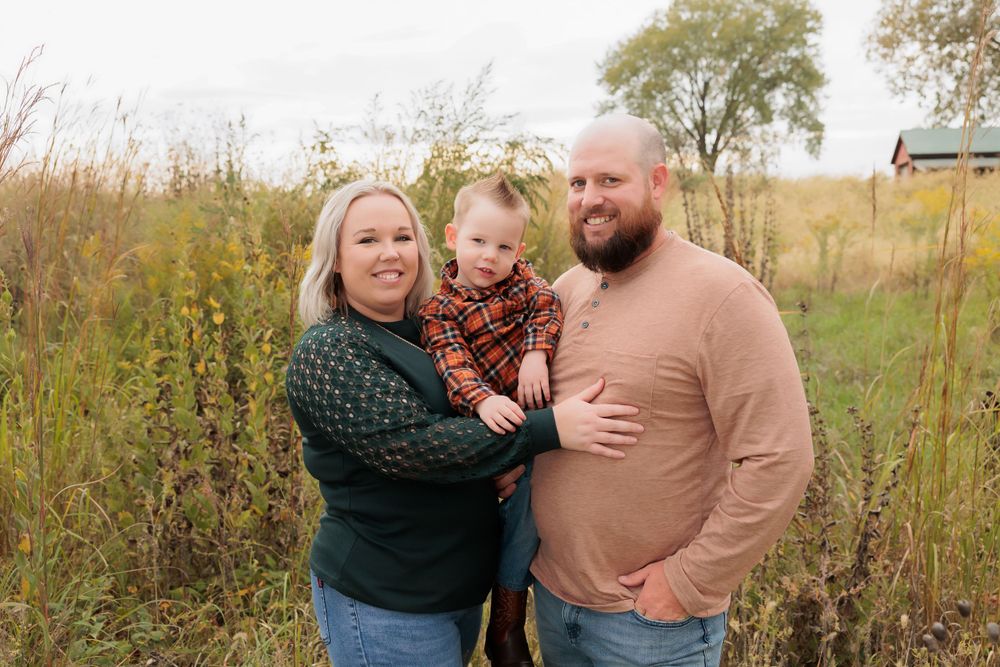 A loving family portrait taken outdoors surrounded by fall prairie grasses.