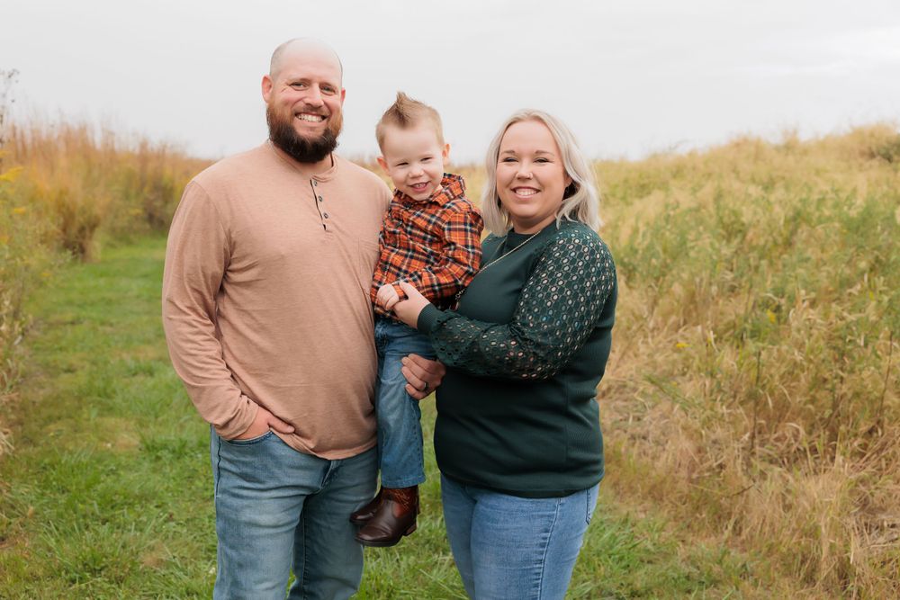 A joyful family photo together on a nature trail surrounded by golden autumn grasses.