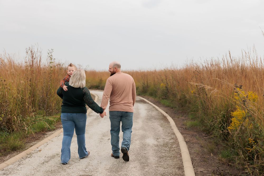 Two people walking together on a winding path through golden prairie grass.