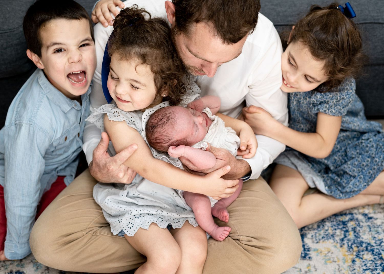 Family of six newborn photograph with dad holding all the kids.