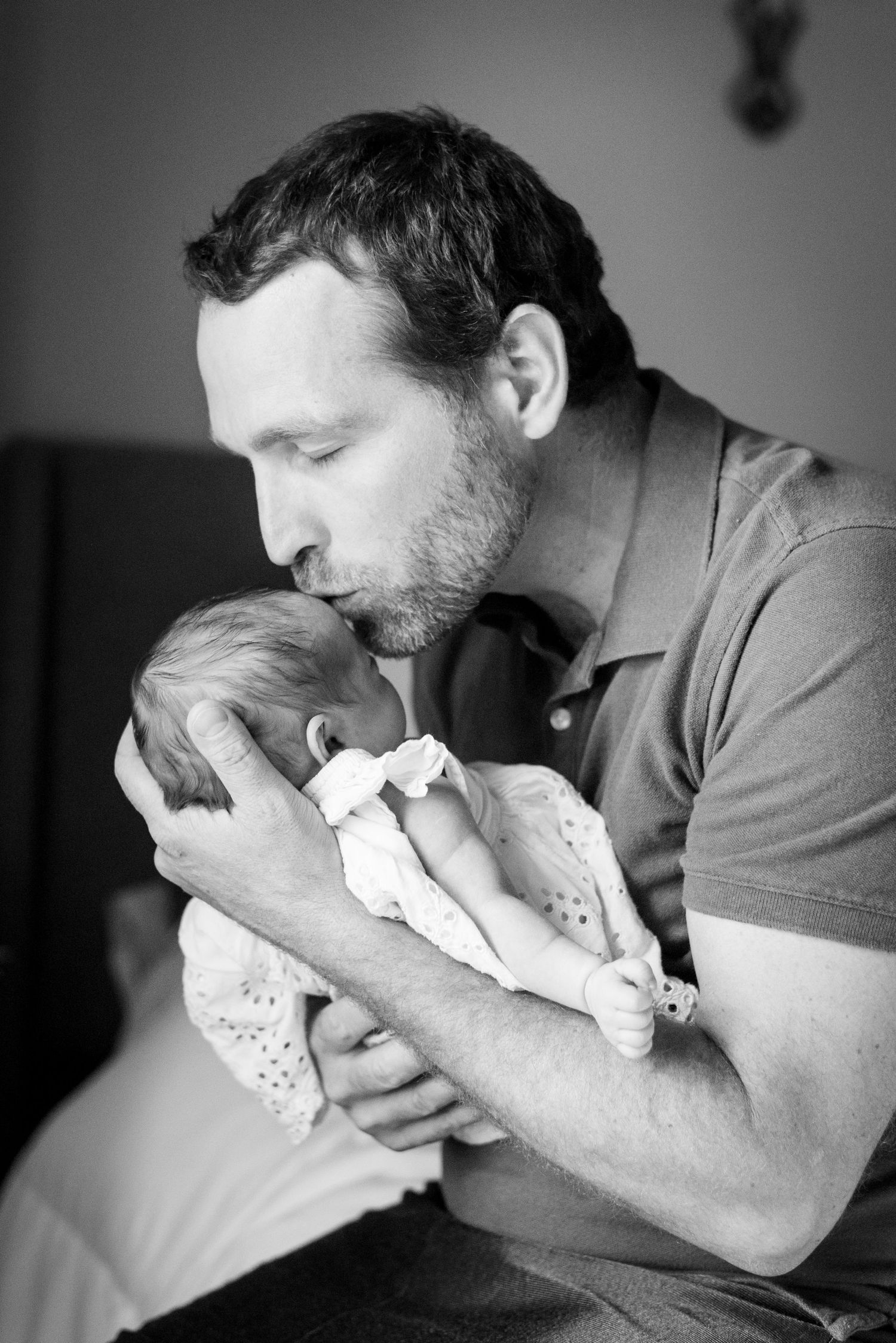 Black and white newborn photograph of dad kissing a newborn baby.