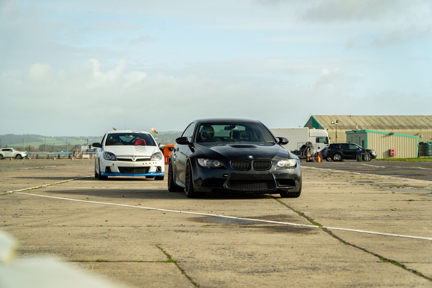 Two BMW cars parked on a concrete surface with coastal scenery in the background.