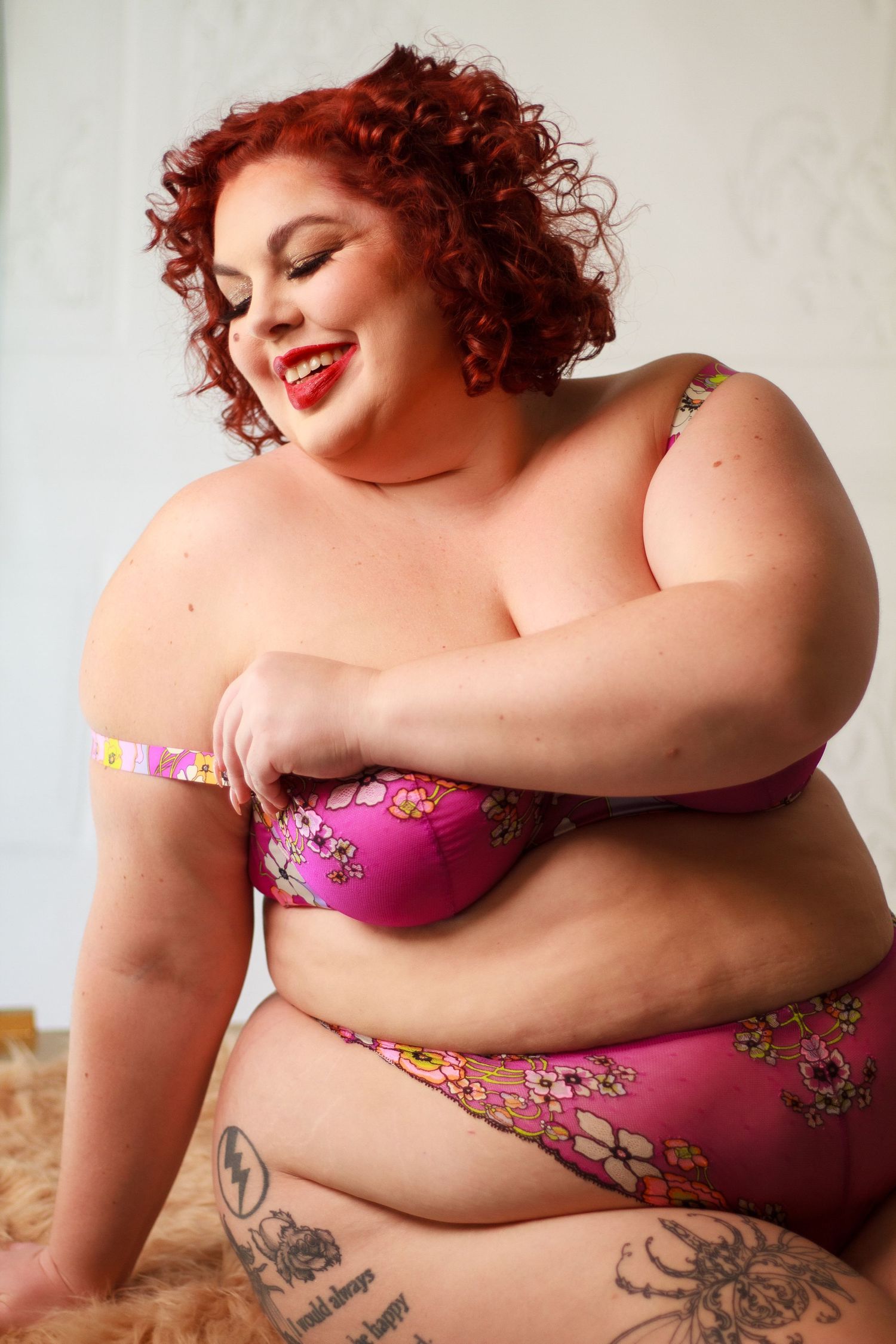 Plus size model laughing during in studio boudoir shoot.