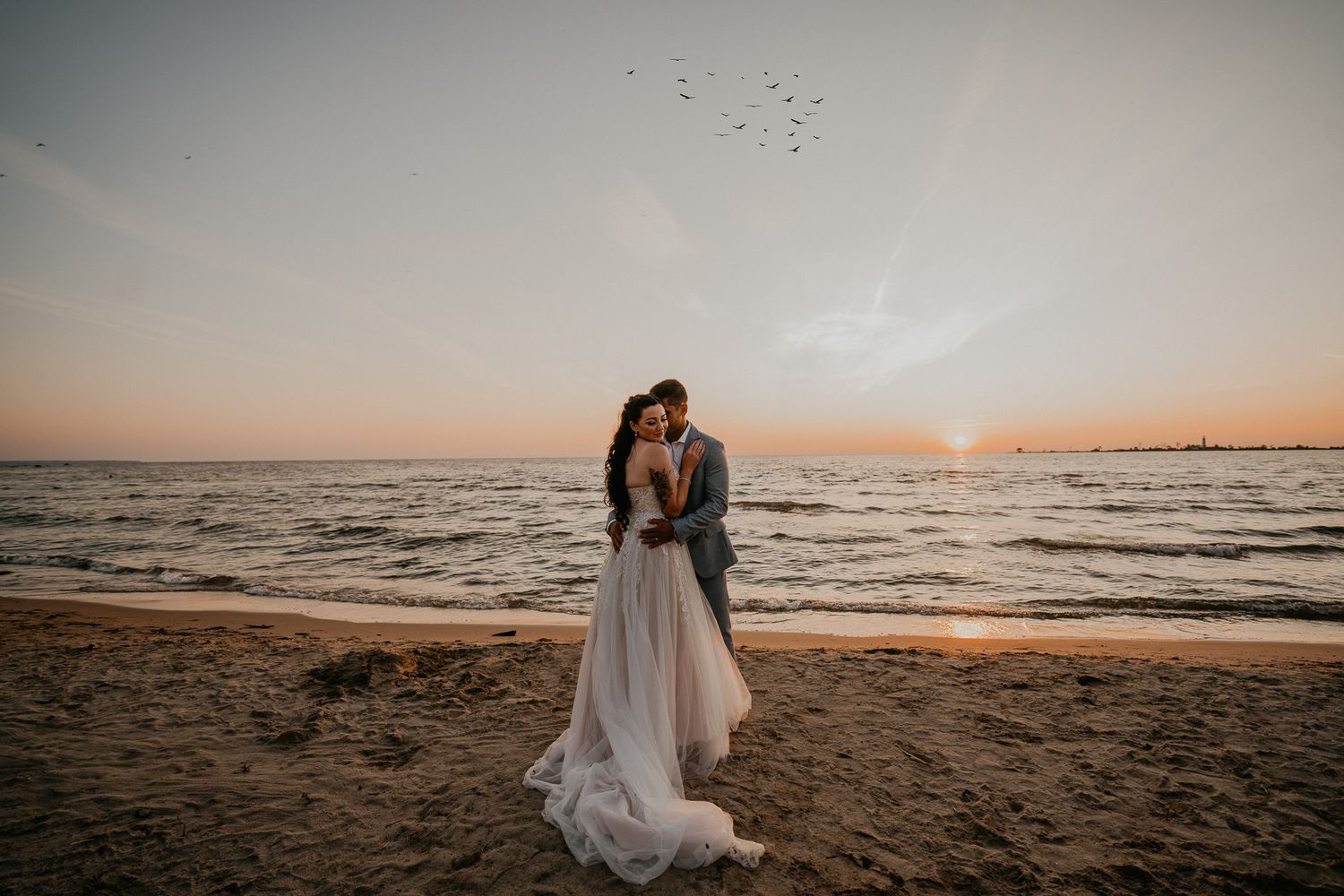 bride turns away as groom snuggles on Beach of Lake Huron