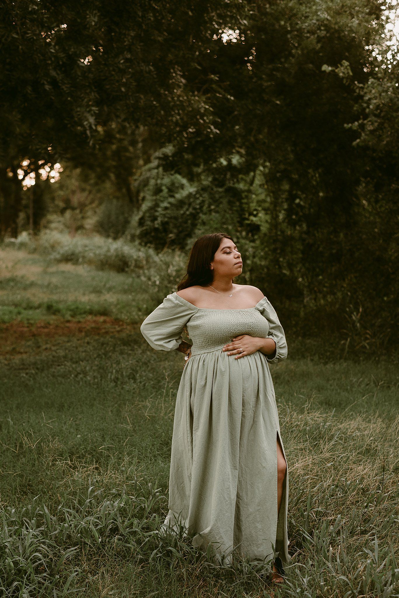 Elegant maternity pose in flowing dress during golden hour.