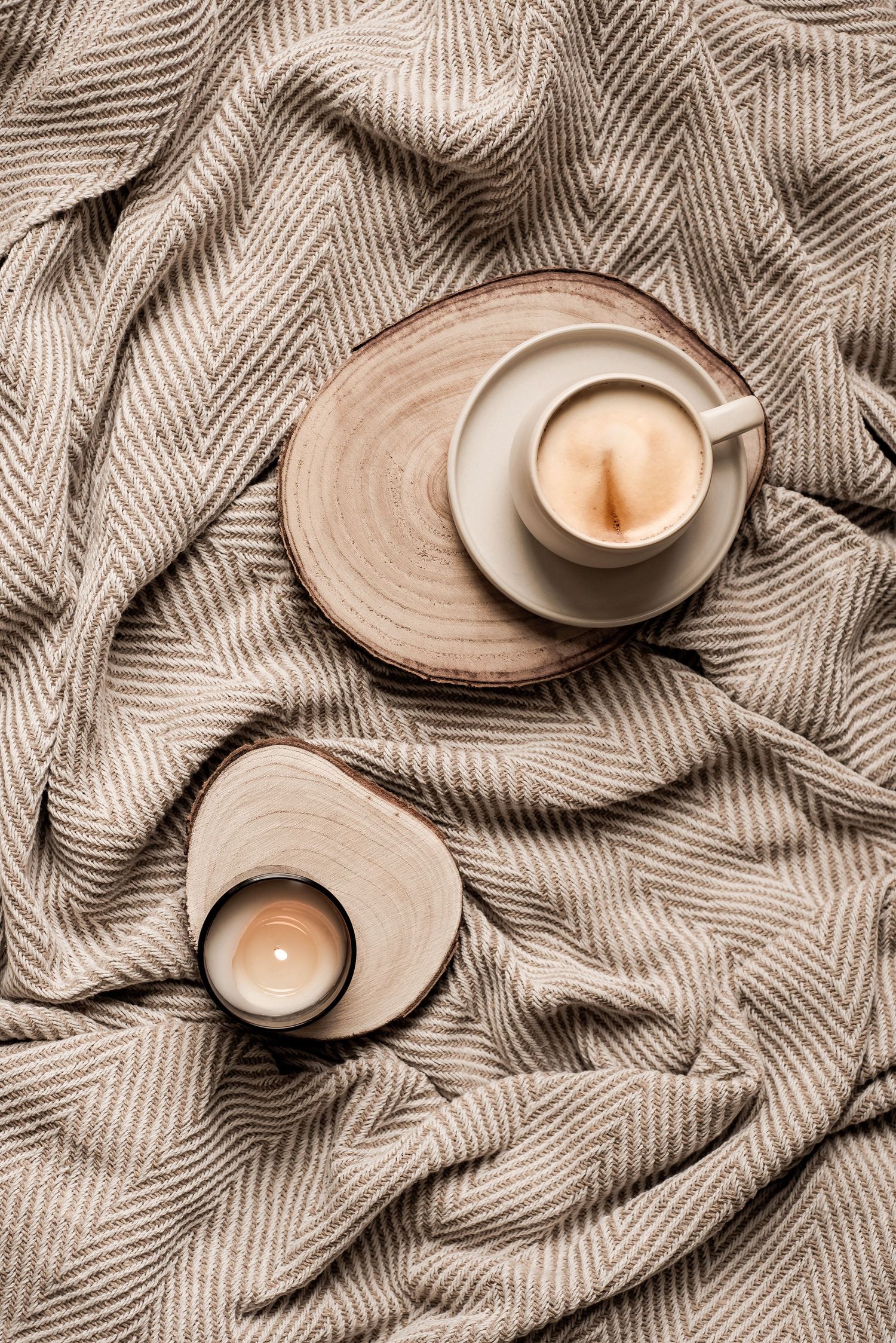 Coffee and candle on wooden slats on top of a cozy blanket. Cozy, inviting, warm, rustic, autumnal