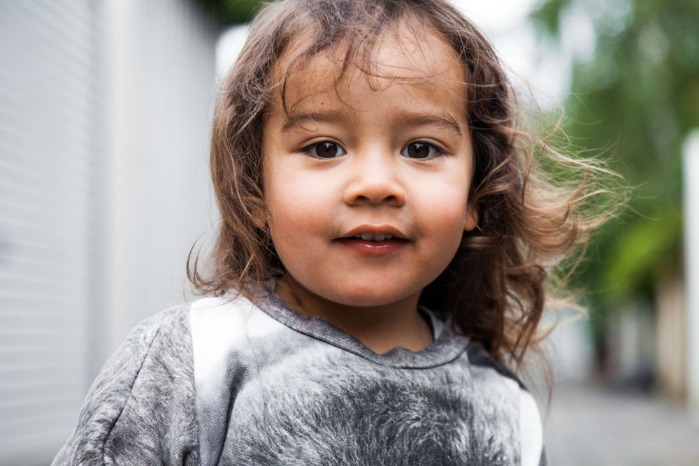Candid portrait of a little boy shows natural expression against outdoor background.