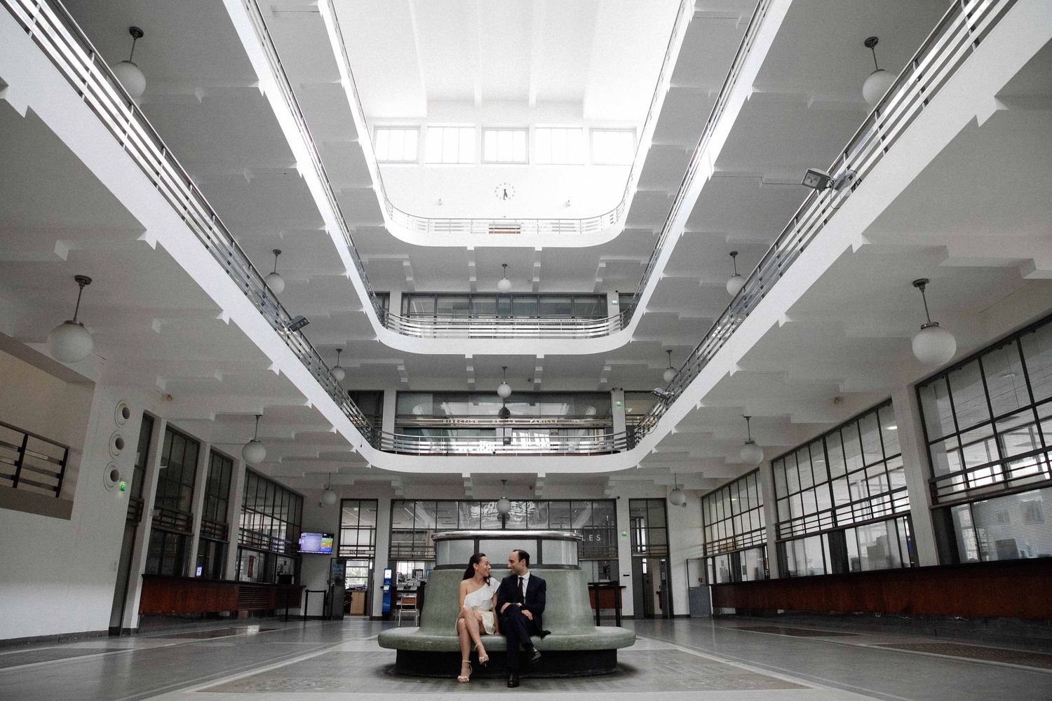 Interior view of a modern building atrium with bright fluorescent lighting and stark white architecture.