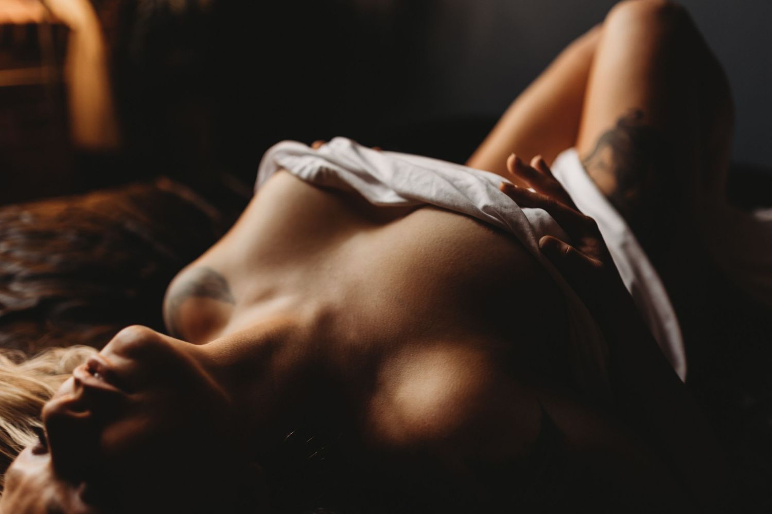 Artistic boudoir photograph showing a resting figure in natural lighting and shadows.
