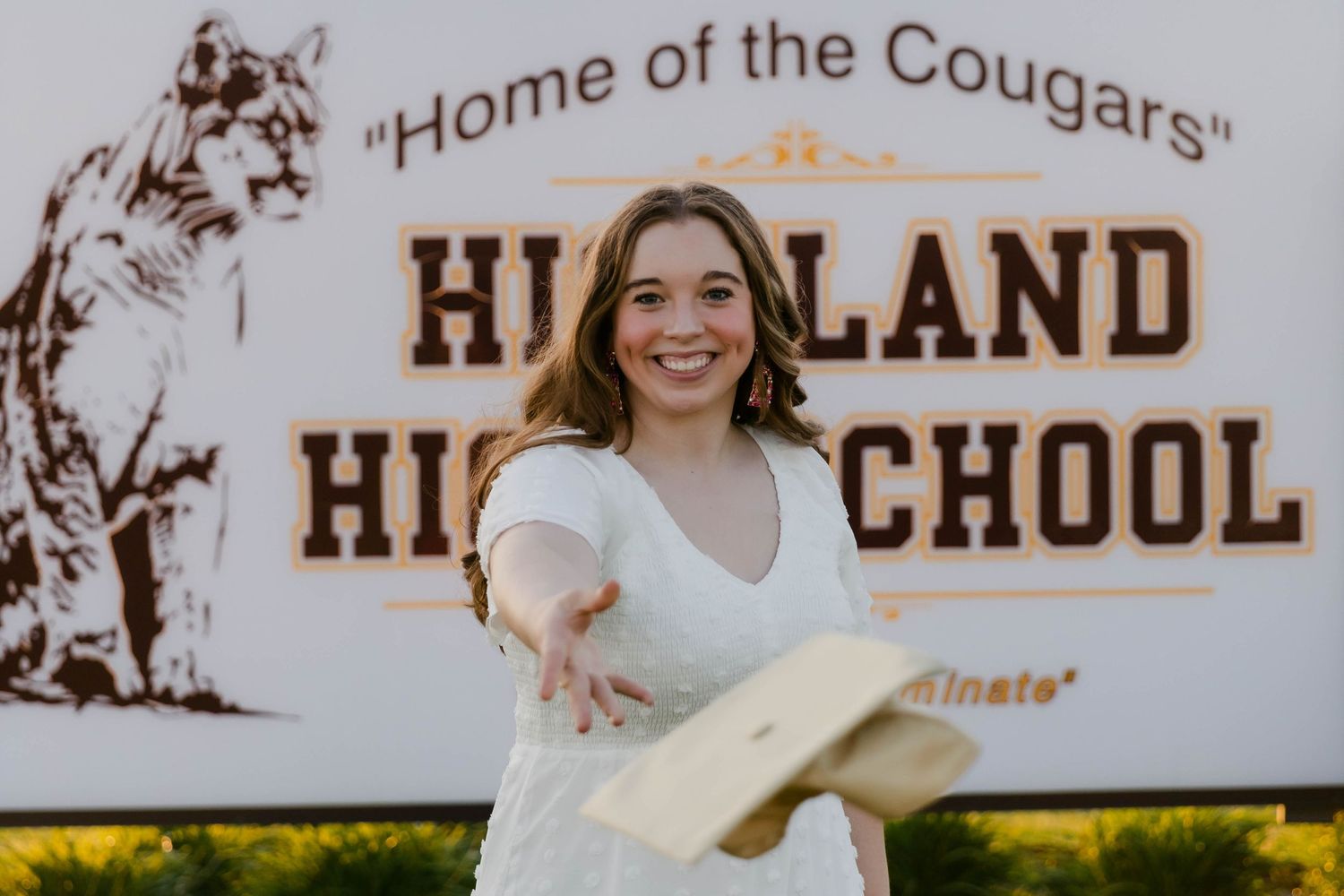 School sign reading 'Highland' with decorative elements in outdoor setting.