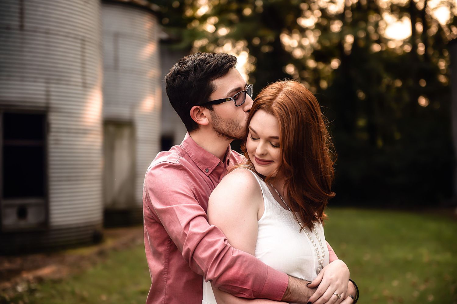 Intimate couple share tender moment in golden sunlit garden setting.