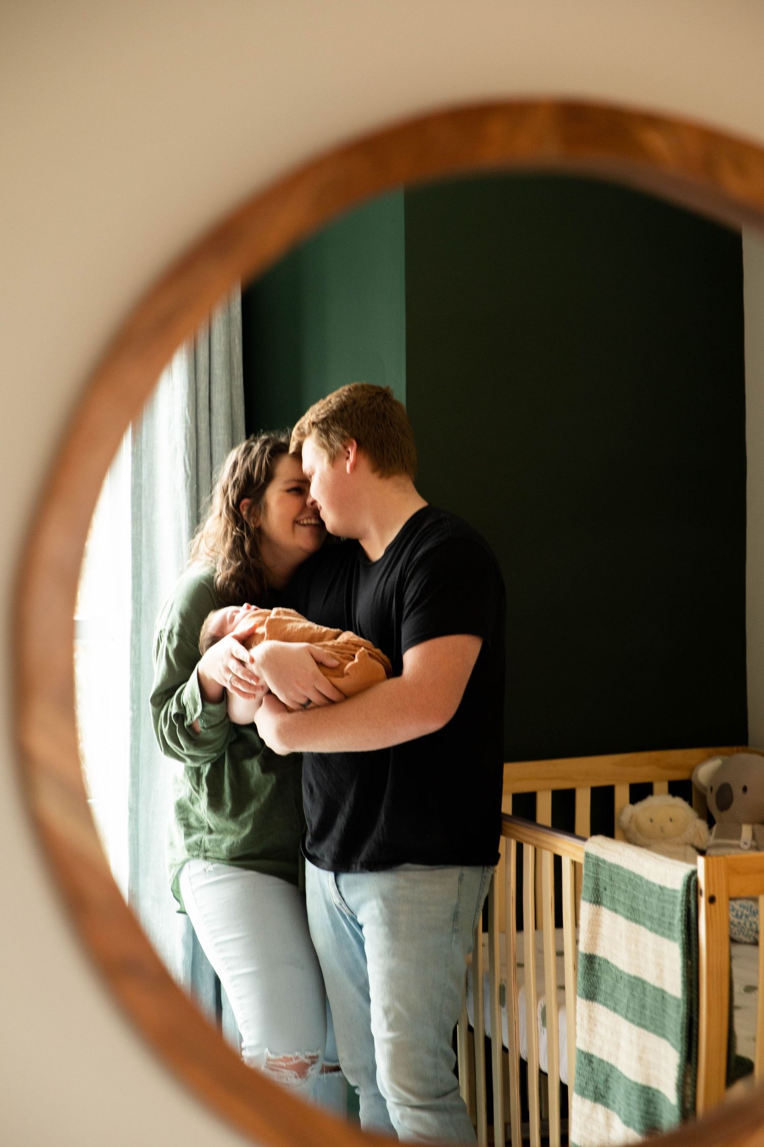 Series of intimate moments captured through a circular mirror frame in a nursery.
