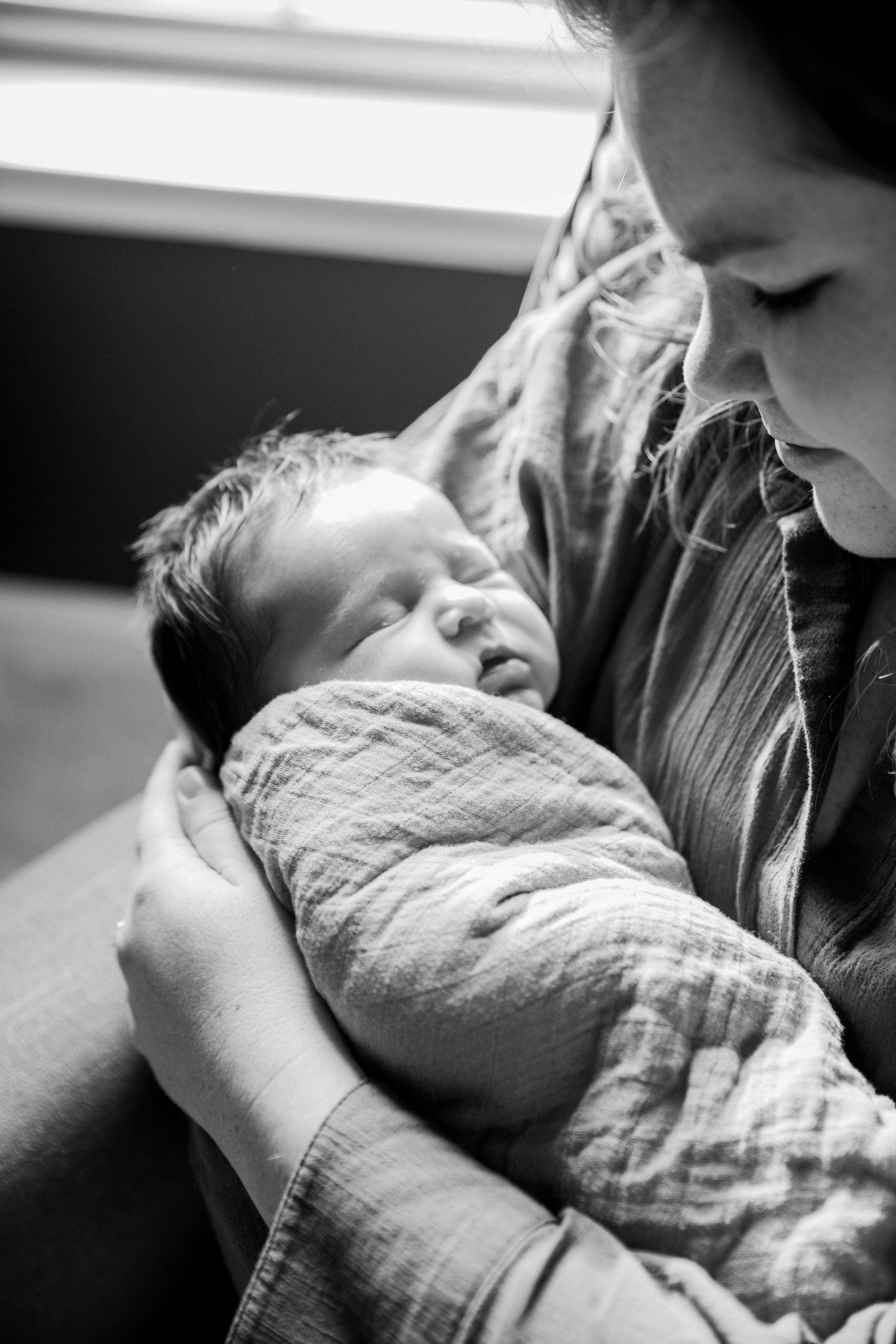 Intimate black and white photography capturing a gentle moment with a newborn.