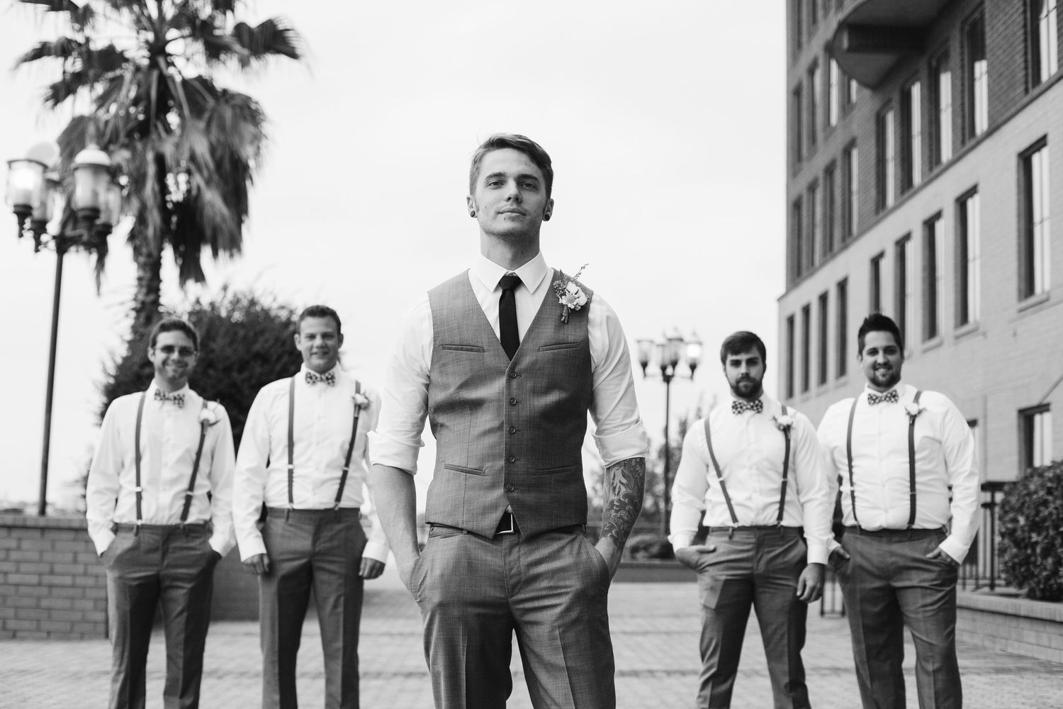 Groomsmen in suspenders and suits posing in black and white photo.