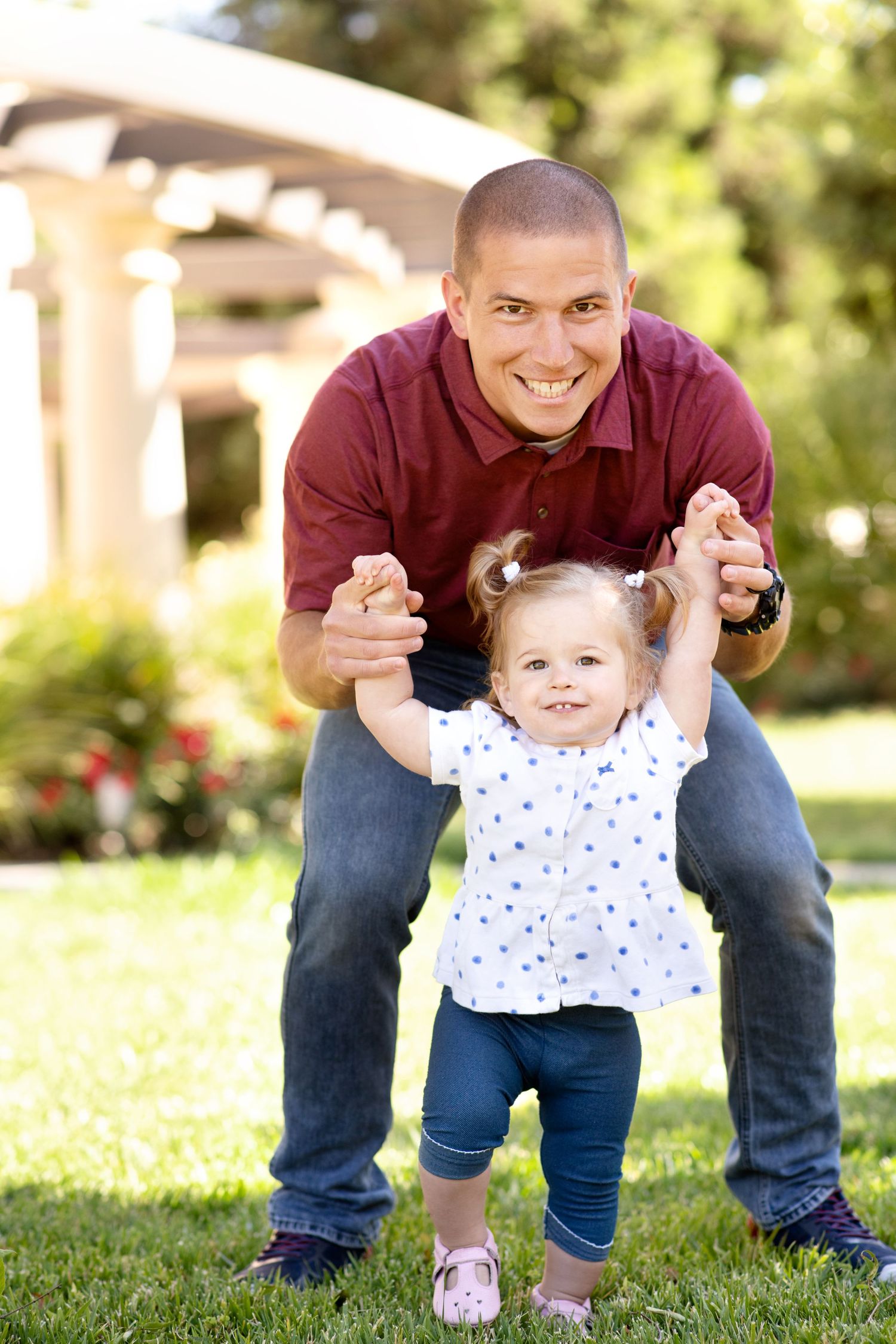 Father and toddler playing together on grass during outdoor photo session.