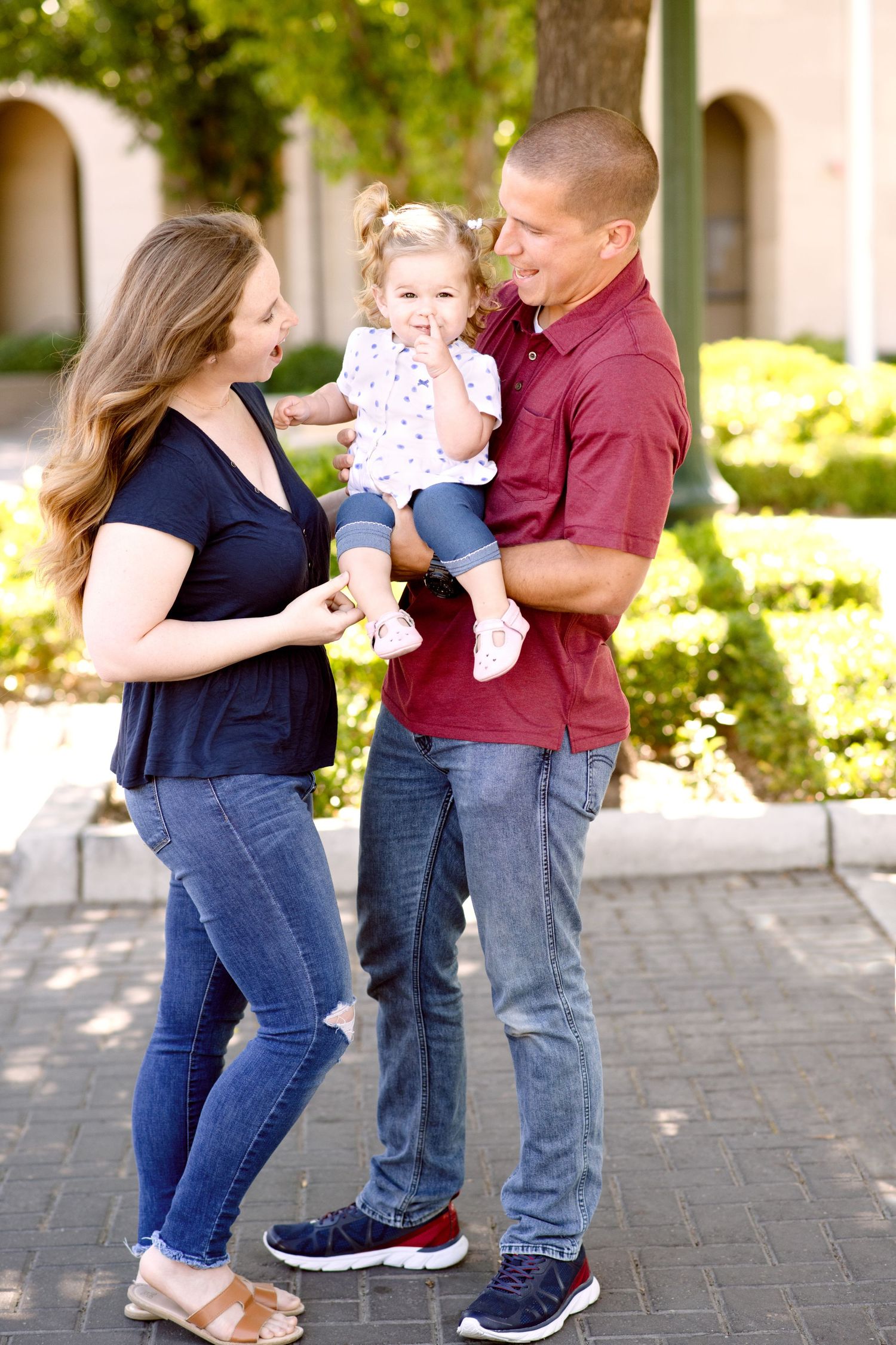 A family shares a candid moment together on a paved walkway with landscaping in the background.