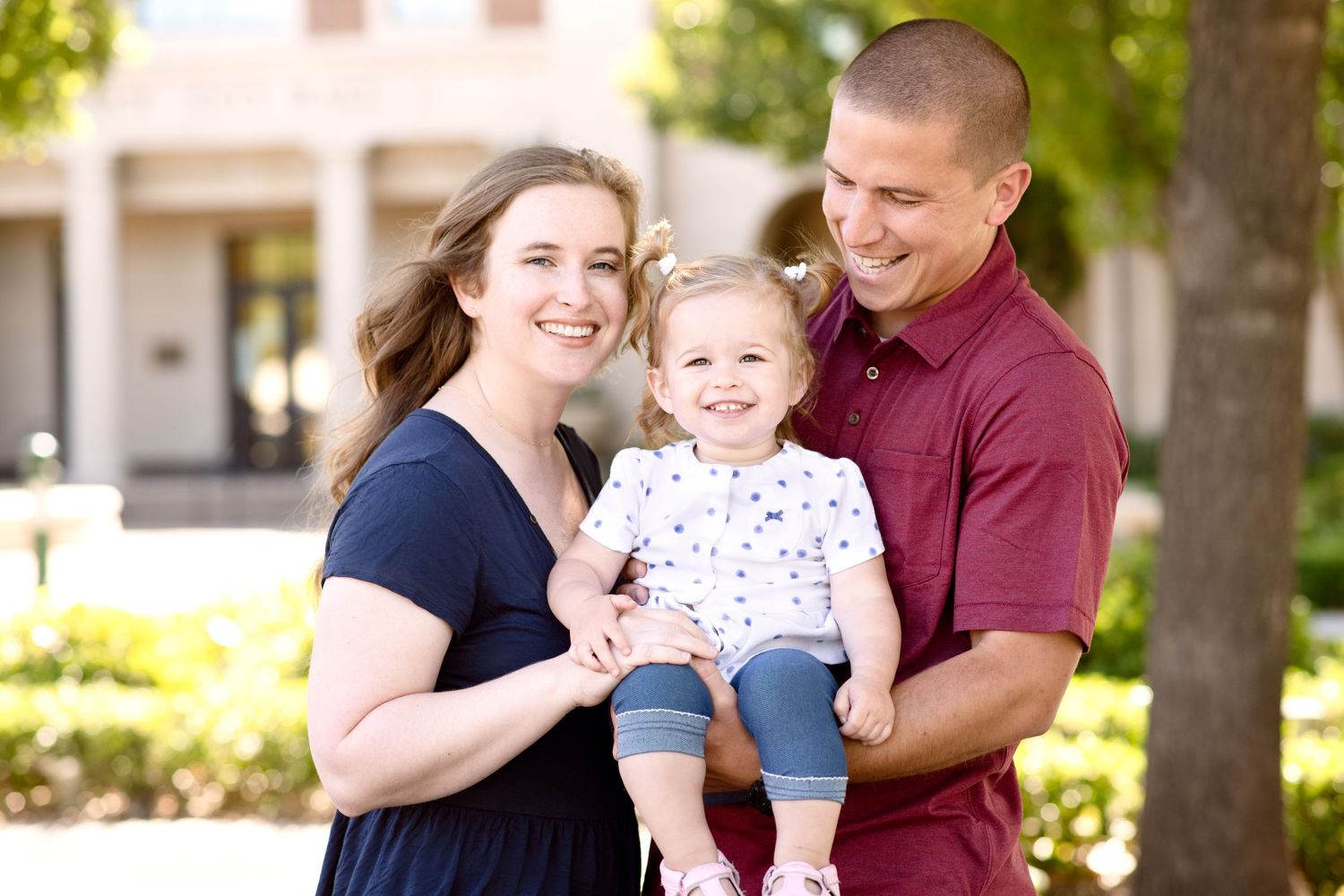 A family of three shares a joyful moment together outside a building.