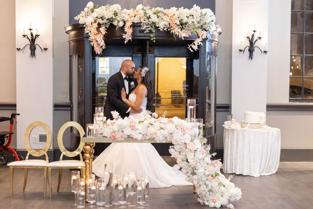 Wedding portrait in front of decorative doorway with floral arrangements and candlelit details.