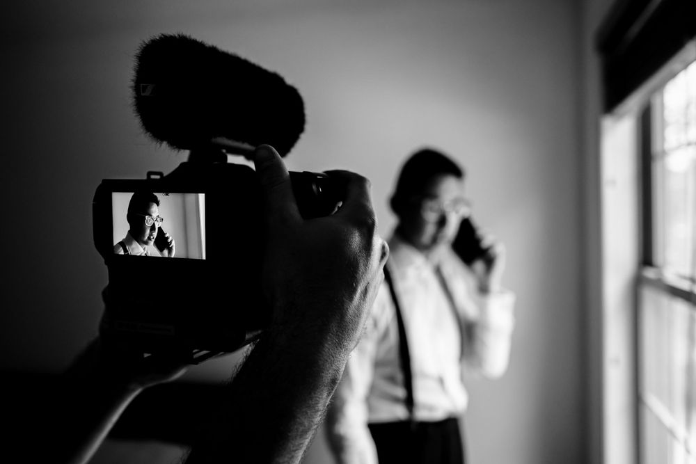 Artistic black and white photography of wedding preparation moments in window light.