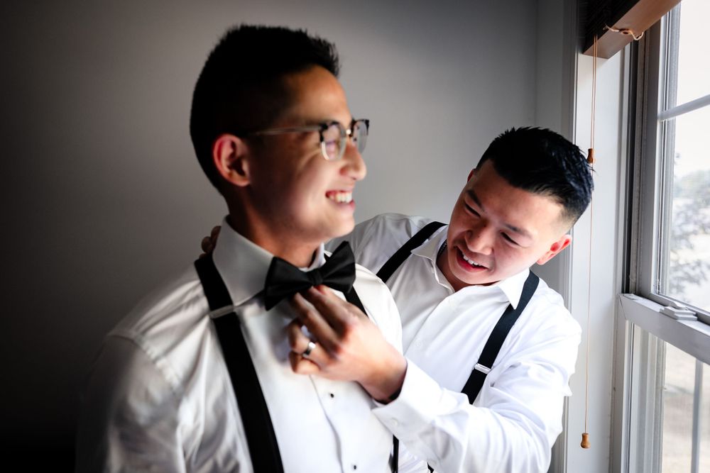Wedding day preparation moments captured through window light in black and white.