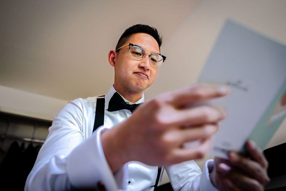 Reading from papers during wedding preparation in natural window lighting.
