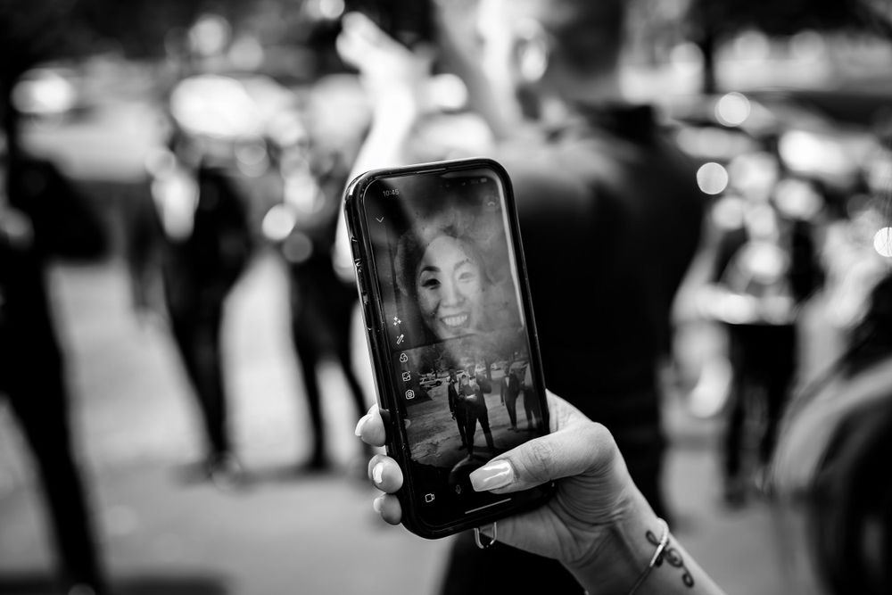 Black and white photo showing guests taking photos with mobile phones at wedding event.