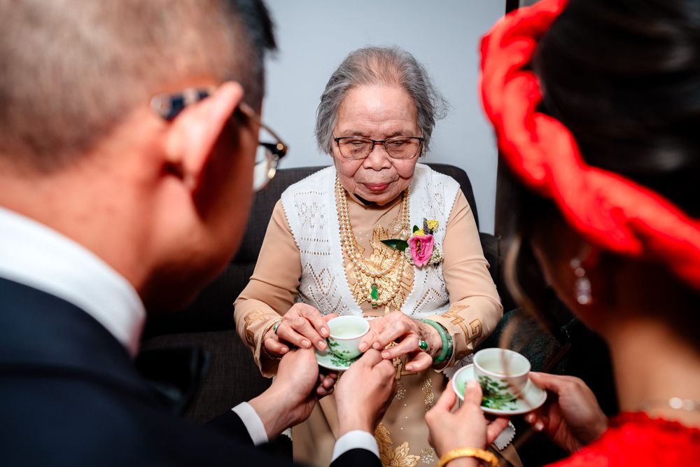Traditional tea ceremony service with hands exchanging ornate cups during wedding celebration.