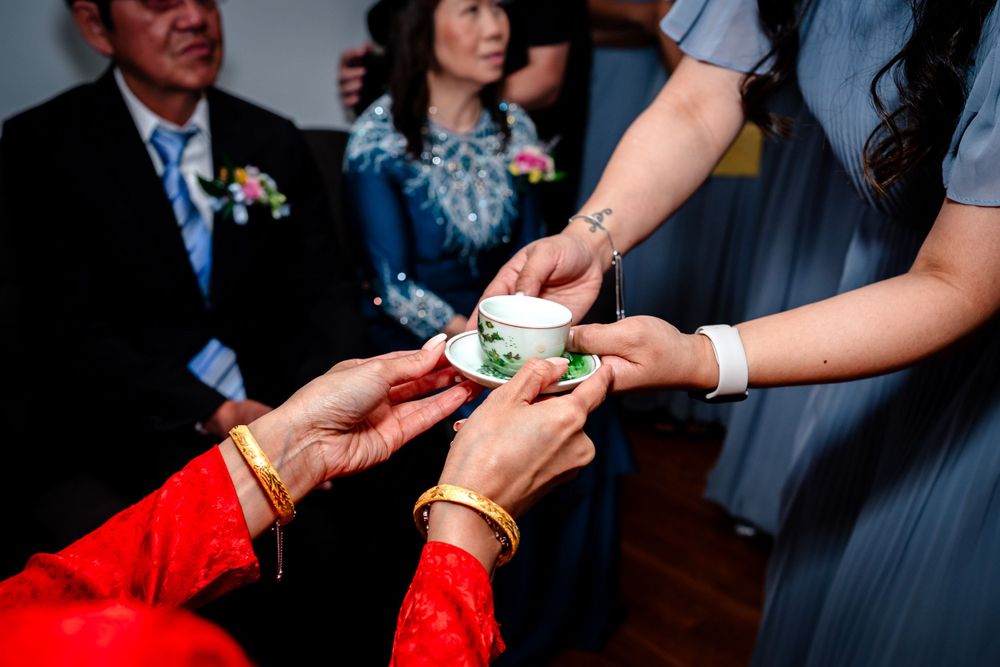 Hands exchange decorative cups during an intimate tea ceremony ritual.