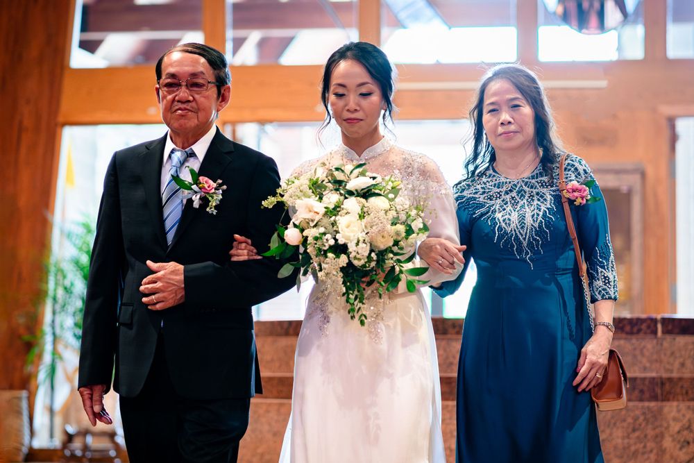 Wedding party members gather in formal attire inside a wooden-beamed church or venue.