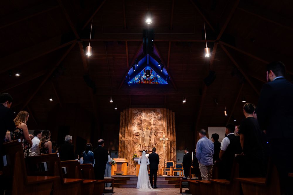Dark interior of church with illuminated altar and cross during wedding ceremony.