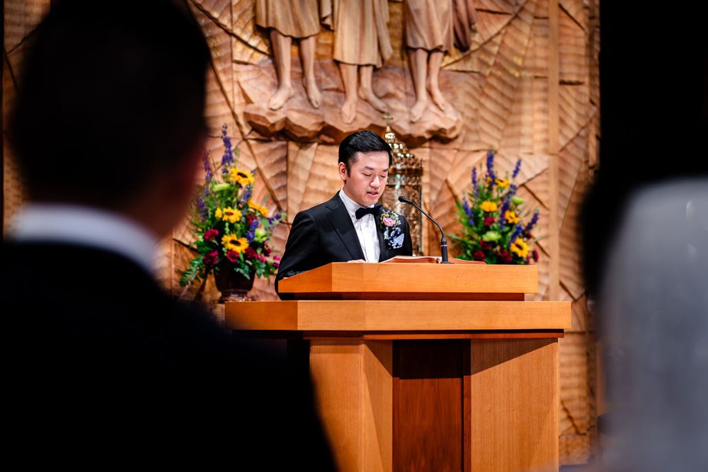 Wedding ceremony taking place at wooden altar with religious artwork in background.