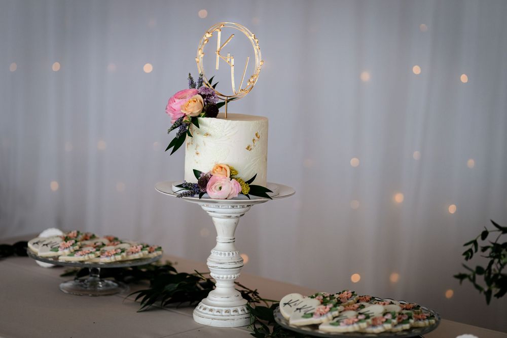 Wedding reception details featuring an elegant white cake with floral decorations and twinkle lights.