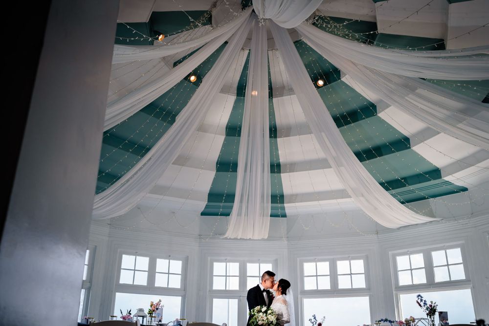 Reception venue ceiling decorated with elegant white fabric draping in a starburst pattern.
