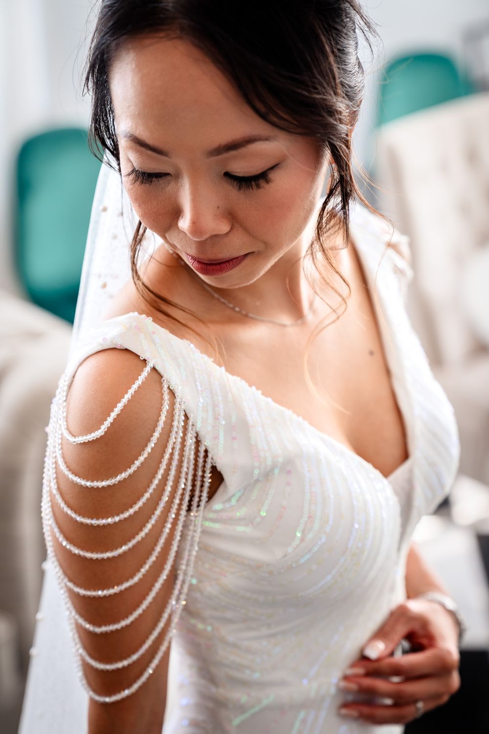 Close-up detail of pearl shoulder jewelry on white wedding dress.