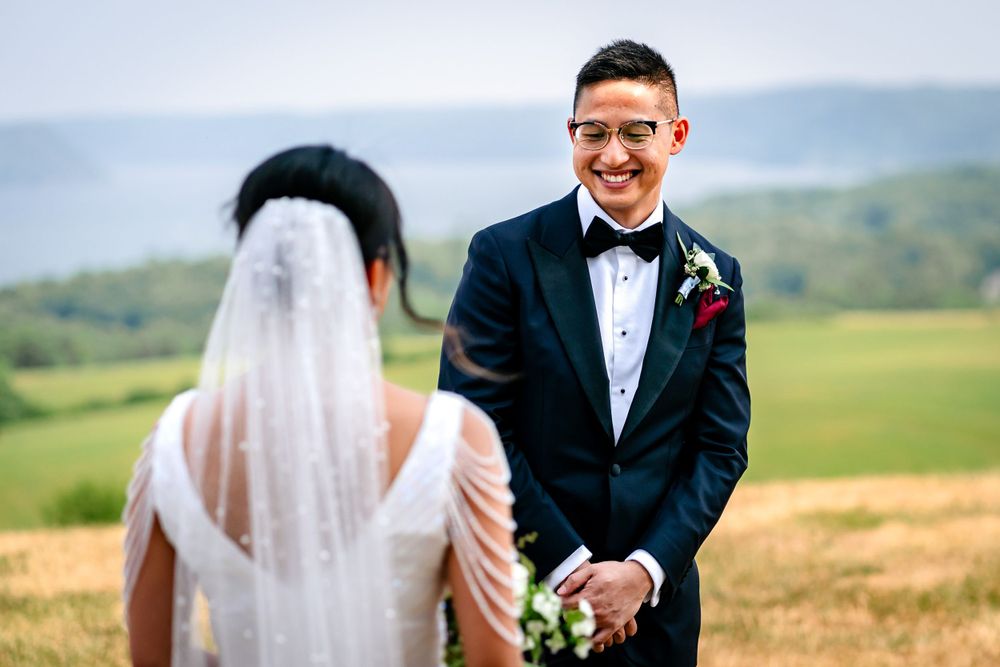 Wedding couple shares tender moments on hilltop with scenic countryside views.