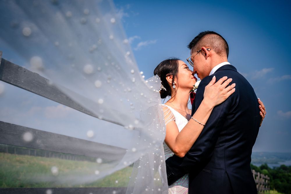 Romantic couple sharing intimate moments against a bright blue sky during their wedding photoshoot.