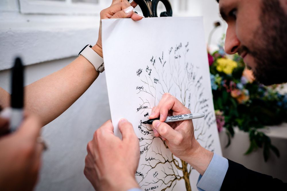 Close-up shots of guests signing the wedding guestbook with pens.