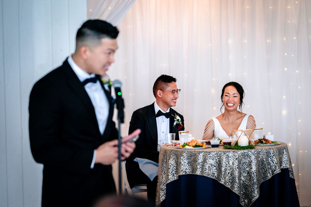 Wedding reception setup with sparkly sequined tablecloths and white backdrop decorations.